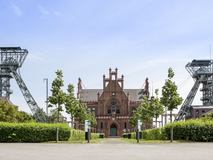 Blick in den Ehrenhof der Zeche Zollern mit der historischen Zechenverwaltung und den beiden Fördergerüsten im Hintergrund (vergrößerte Bildansicht wird geöffnet)