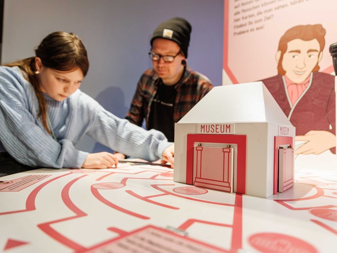 Ein Mädchen steht mit einem Mann in der Ausstellung an einem Exponat und arbeitet an diesem