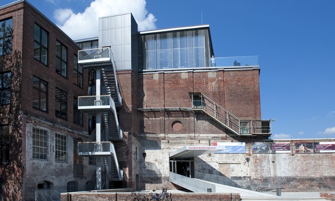 Blick auf das Gebäude des Textilwerks Bocholt mit Eingang und dem Glaspavillon auf dem Dach.