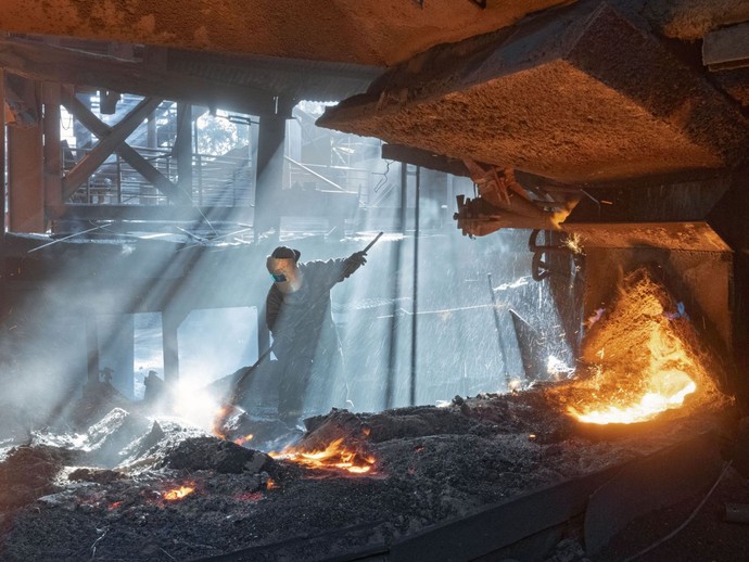Stahlarbeiter bei der Arbeit, umgeben von Glut Stahlarbeiter bei der Arbeit, umgeben von Glut