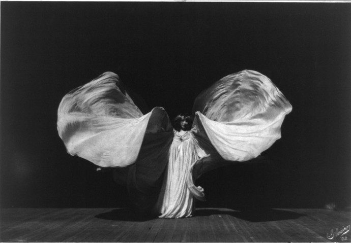 Schwarz-Weiß-Aufnahme von Loïe Fuller beim Tanz mit wehendem Stoff