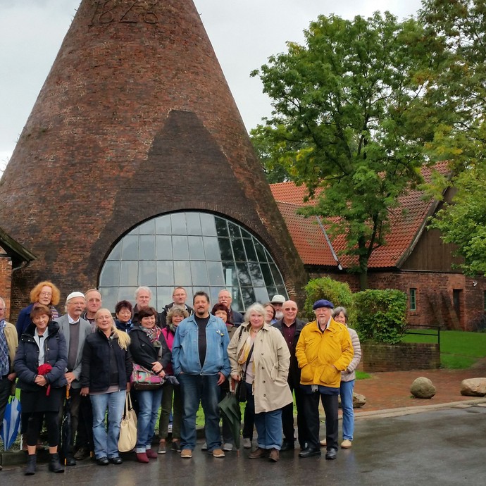 Gruppe von Menschen vor dem Glasturm der Glashütte Gernheim (vergrößerte Bildansicht wird geöffnet)